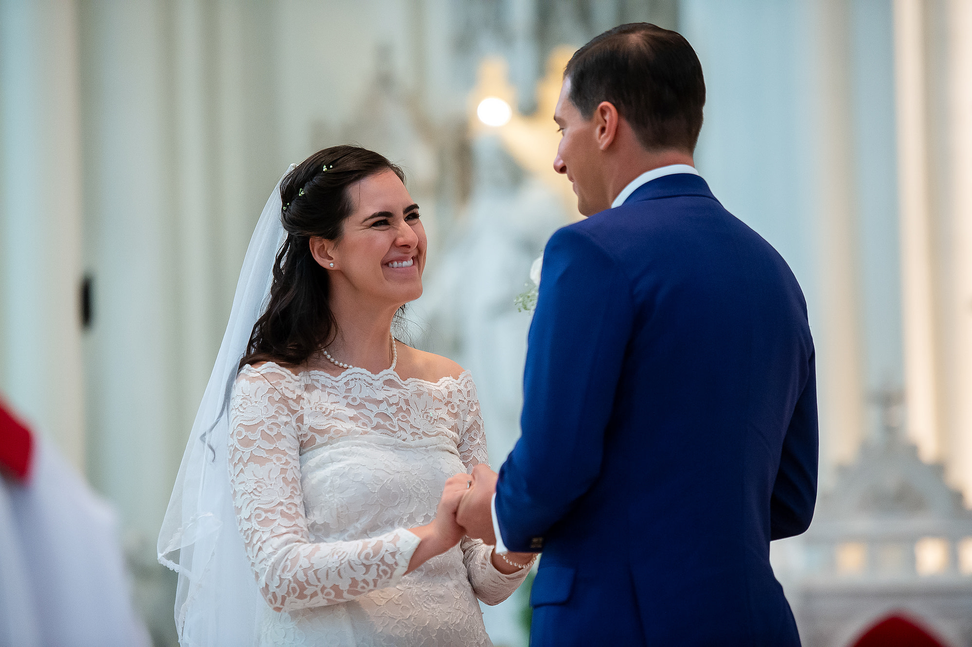 Bride smiles at groom during their wedding at the Cathedral Basilica of the Immaculate Conception in Denver, Colorado.