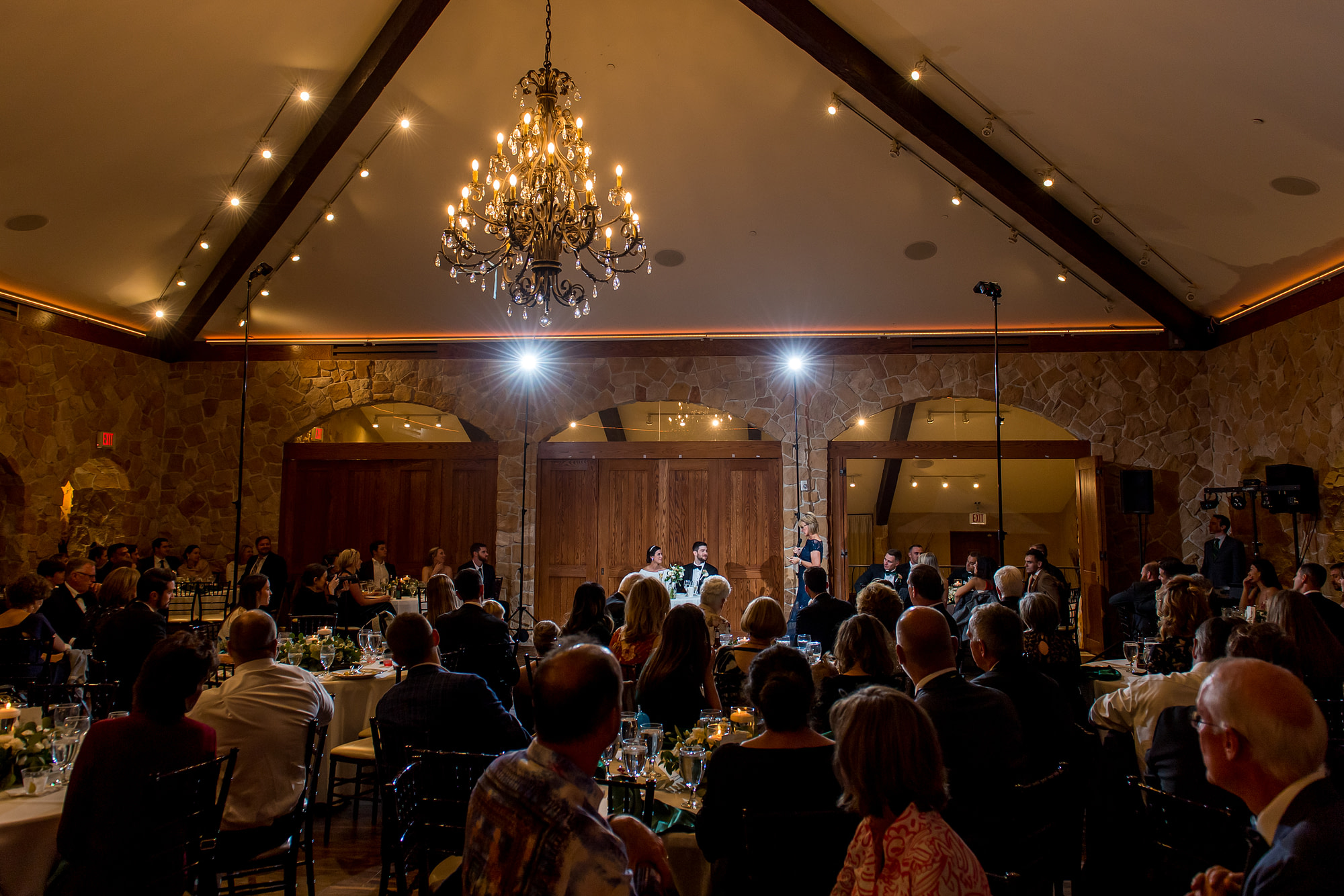 Bride and groom smile during toasts at Baldoria on the Water wedding venue in Lakewood, Colorado.