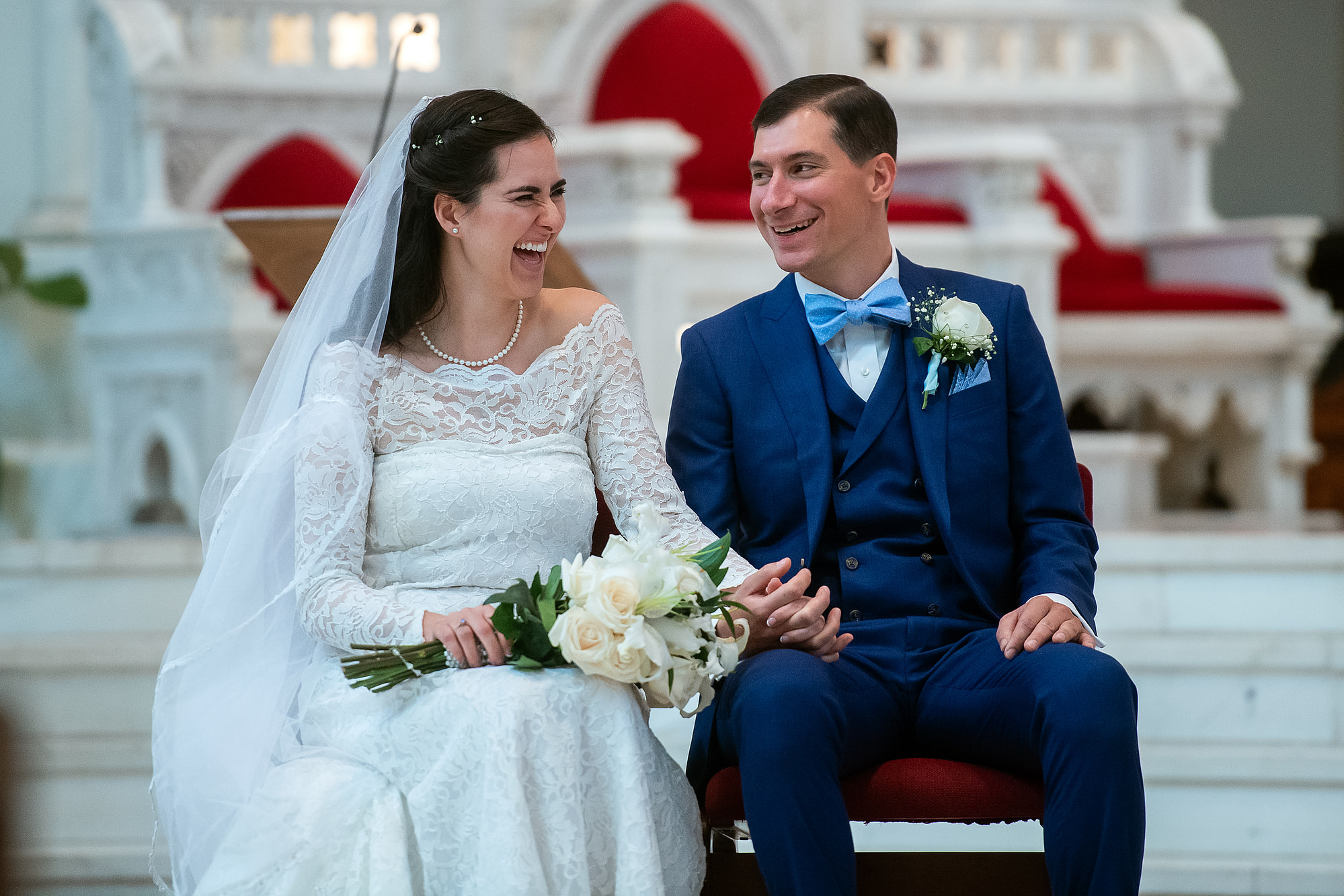 Bride and groom laugh during their wedding at the Cathedral Basilica of the Immaculate Conception in Denver, Colorado.