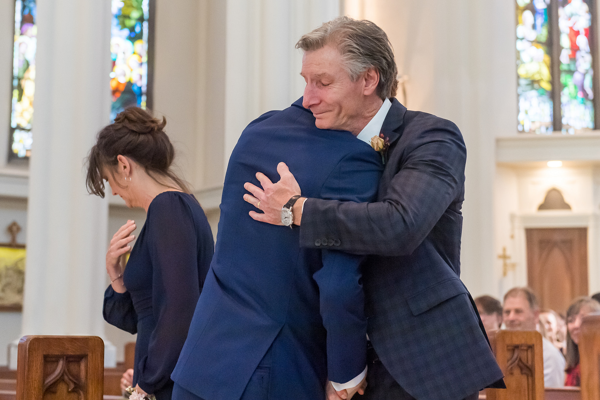 The father of the groom hugs him during his Cathedral Basilica of the Immaculate Conception wedding in Denver, Colorado.