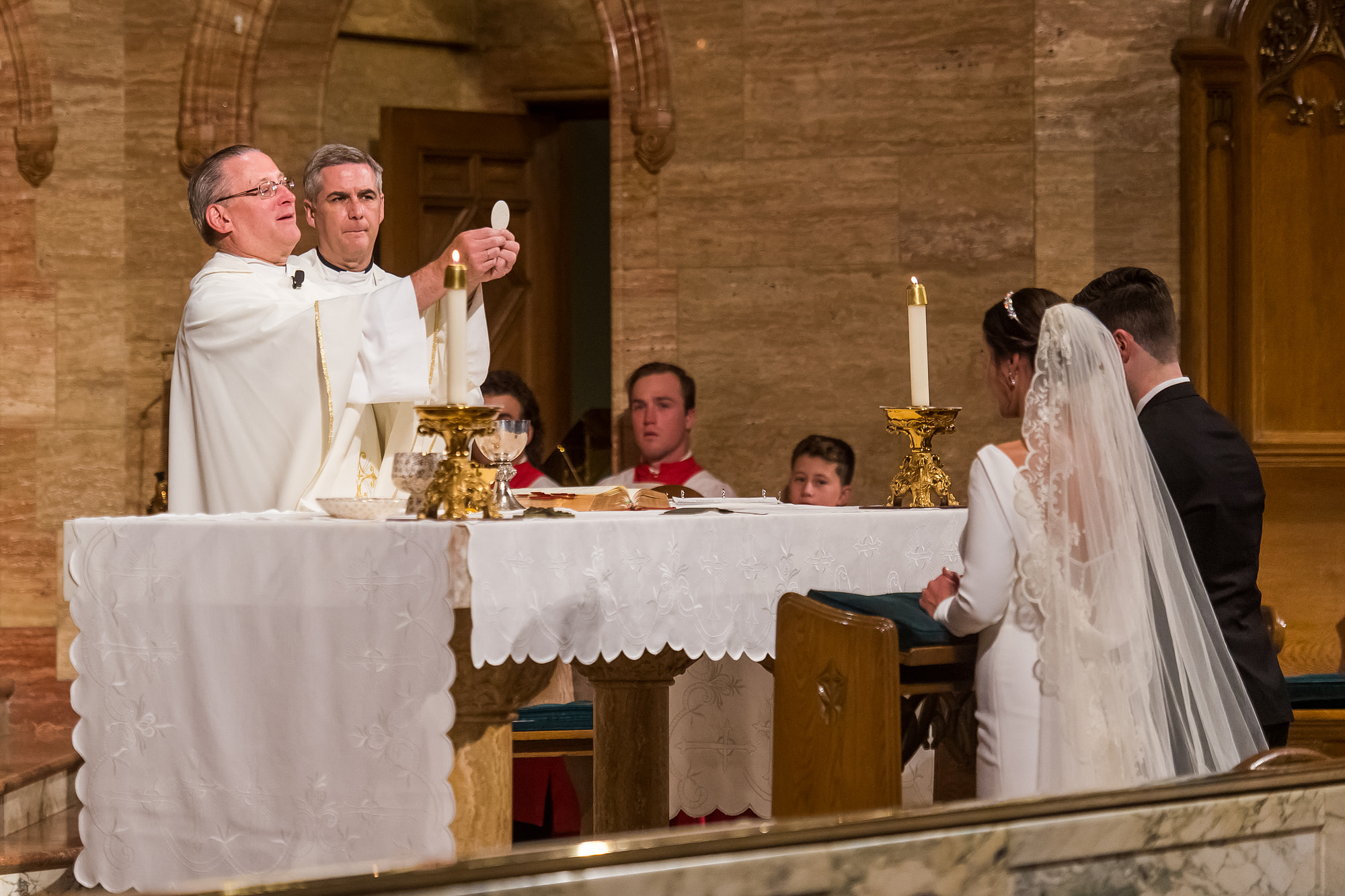 Bride and groom bow their heads during their Holy Ghost Church Denver wedding Mass in Denver, Colorado.
