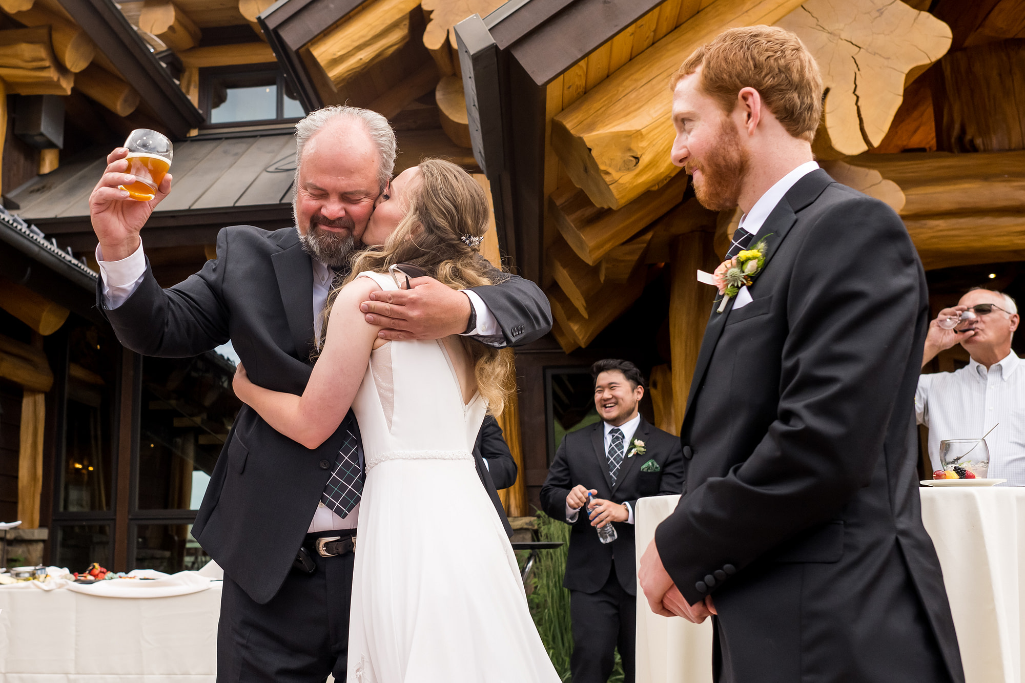 The bride kisses her father after a toast as the groom looks on during their wedding in Telluride, Colorado.