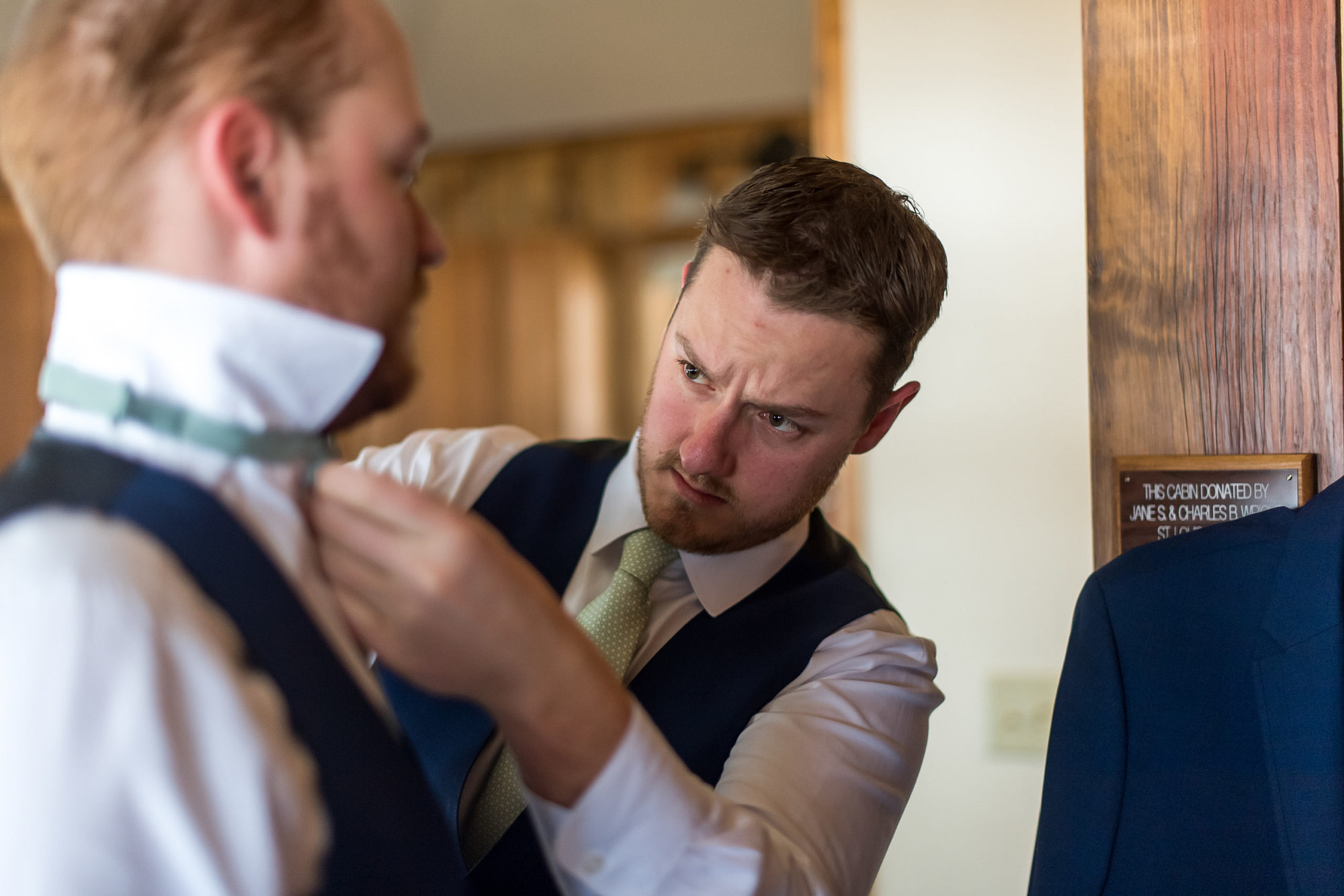 The groom adjusts the tie of a groomsman during his YMCA of the Rockies wedding in Estes Park, Colorado.