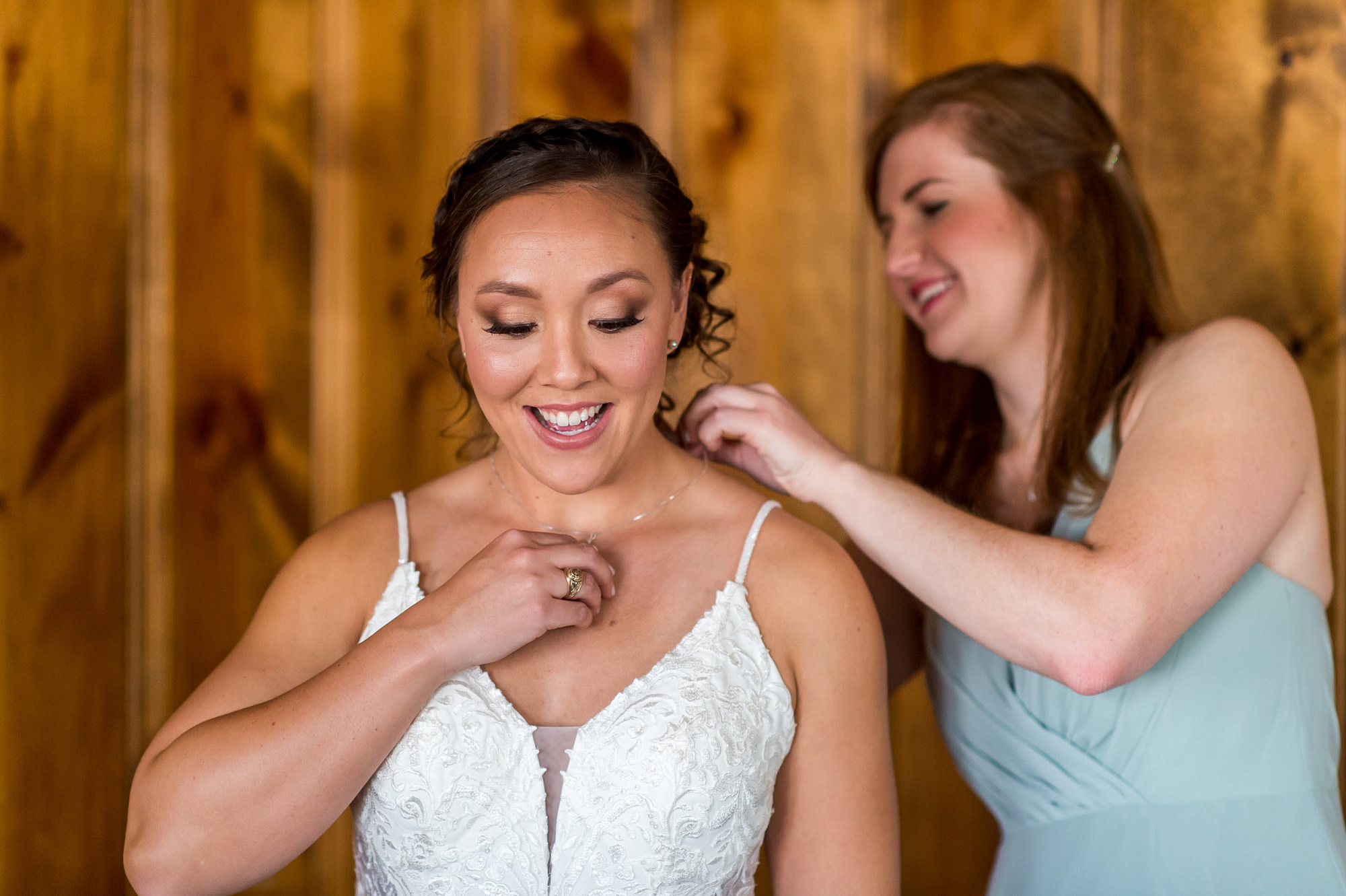 A bridesmaid puts on a necklace during the YMCA of the Rockies wedding in Estes Park, Colorado.