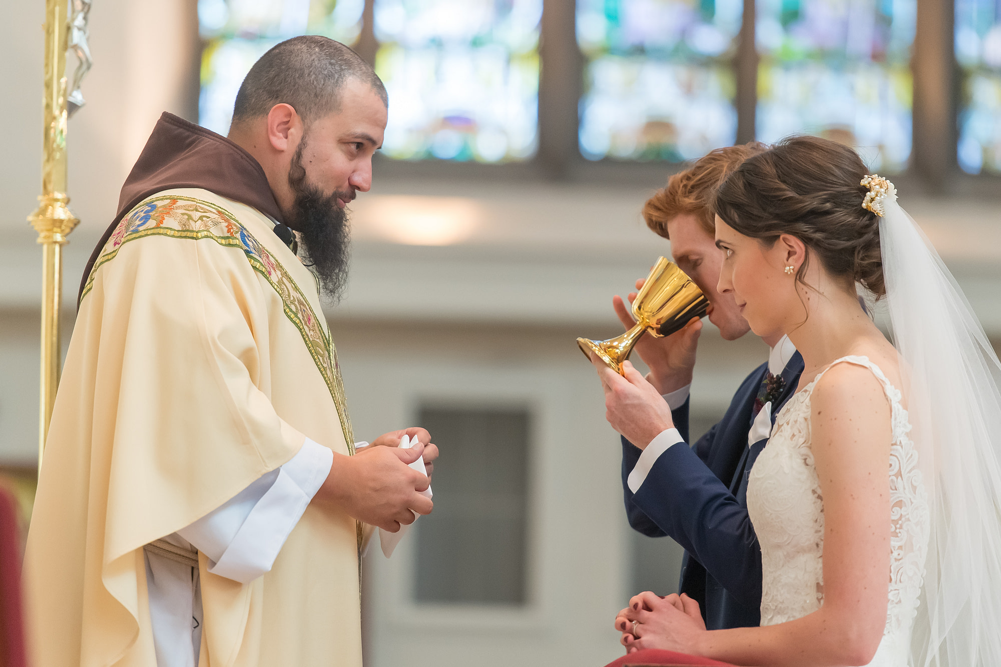 Groom drinks consecrated wine during a Cathedral Basilica of the Immaculate Conception wedding in Denver, Colorado.