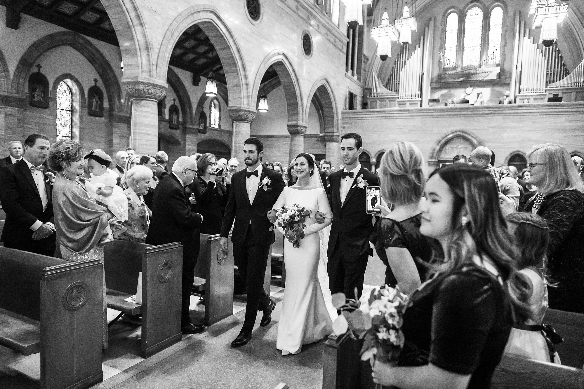 Bride walks down the aisle with her brothers during Holy Ghost Church Denver wedding in Denver, Colorado.