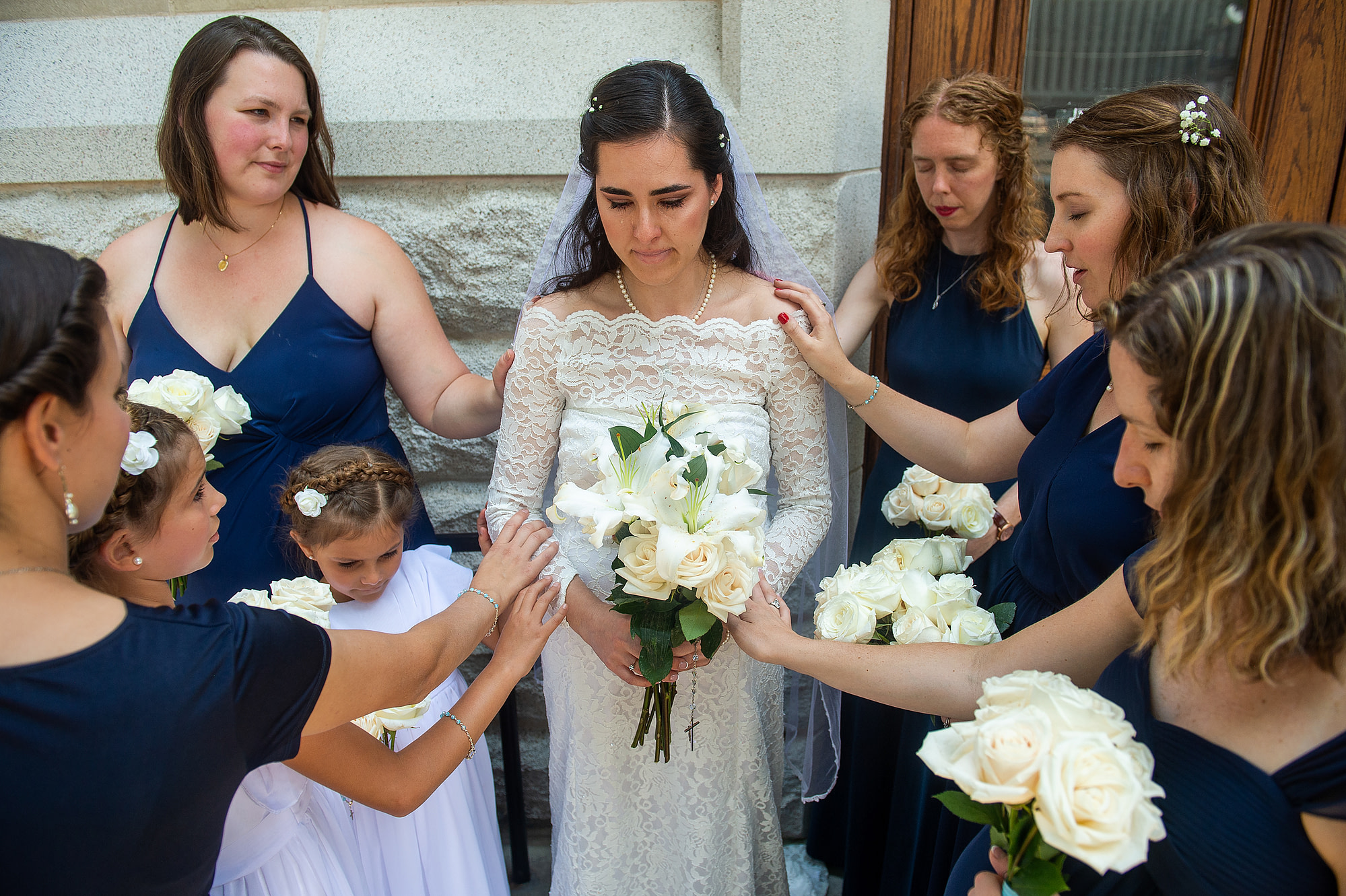 Bride is prayed over while crying before her wedding at the Cathedral Basilica of the Immaculate Conception in Denver, Colorado.